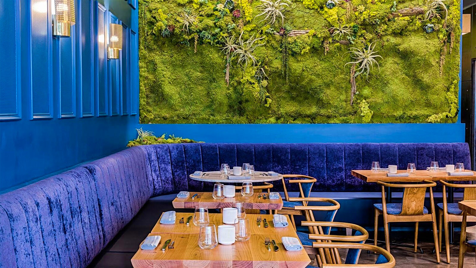The contemporary-design dining room at Bresca, with blue wall paneling, blue banquets and blue tiles on the bar, as well as beige-gray wooden chairs